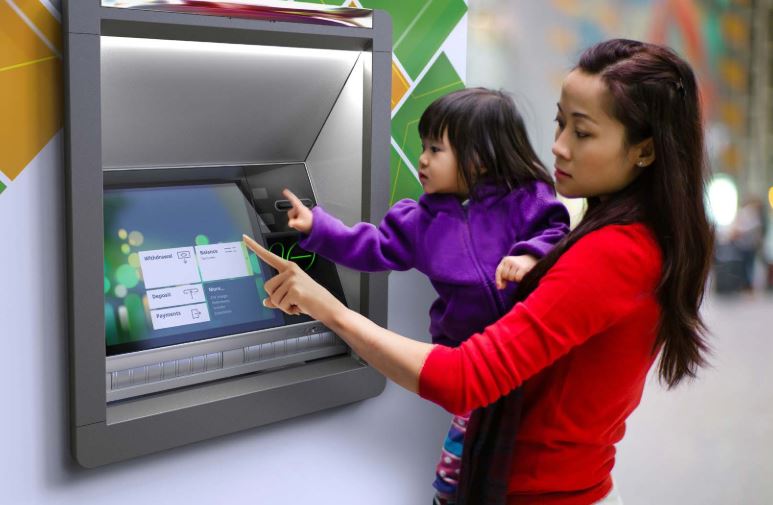 Woman holding child using ATM. ATMs are unmatched for convenience, and QSI is unmatched for ATM expertise.